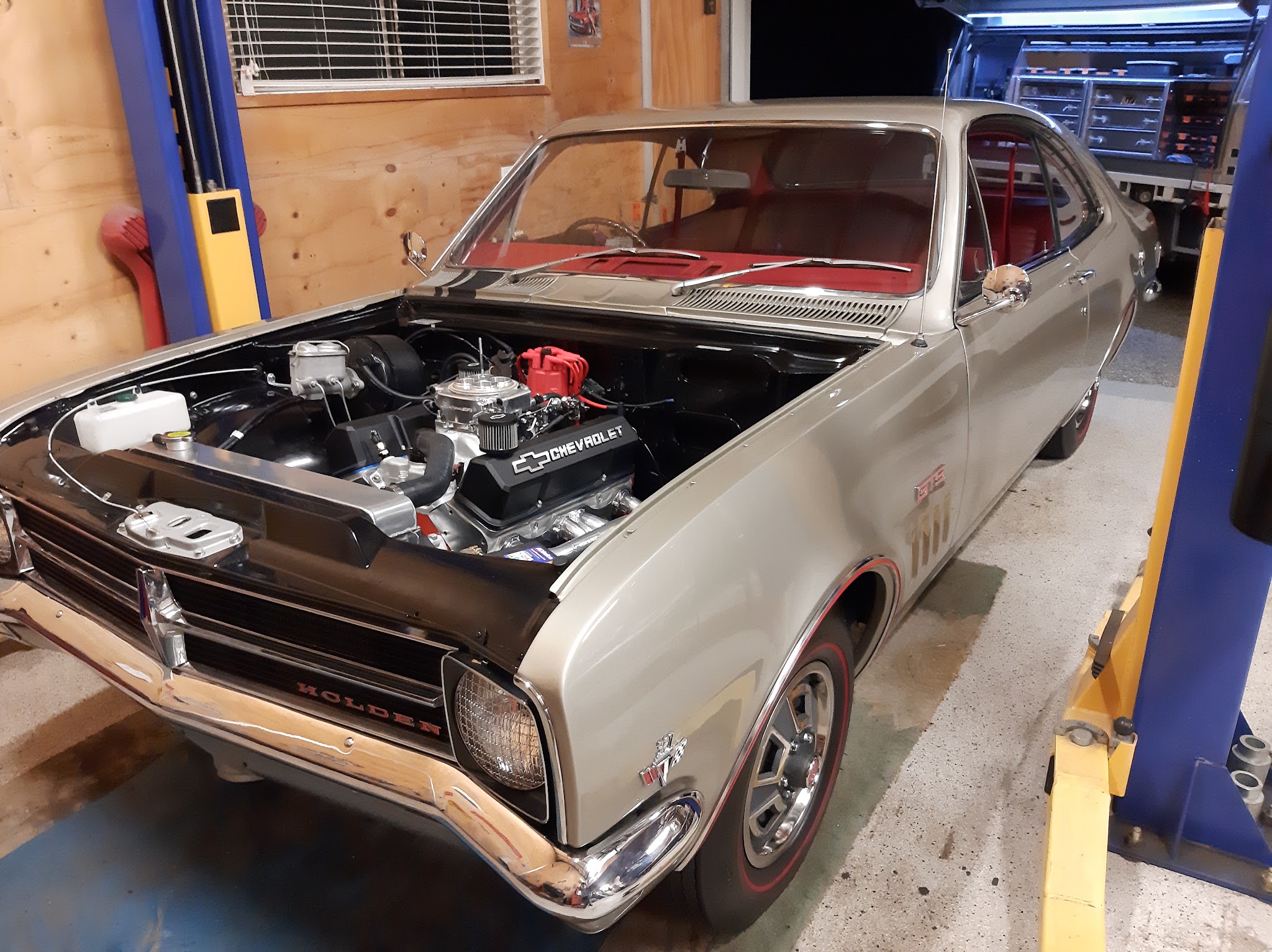 Holden Monaro GTS up on the hoist in the workshop with its bonnet open and a Chevrolet V8 fitted