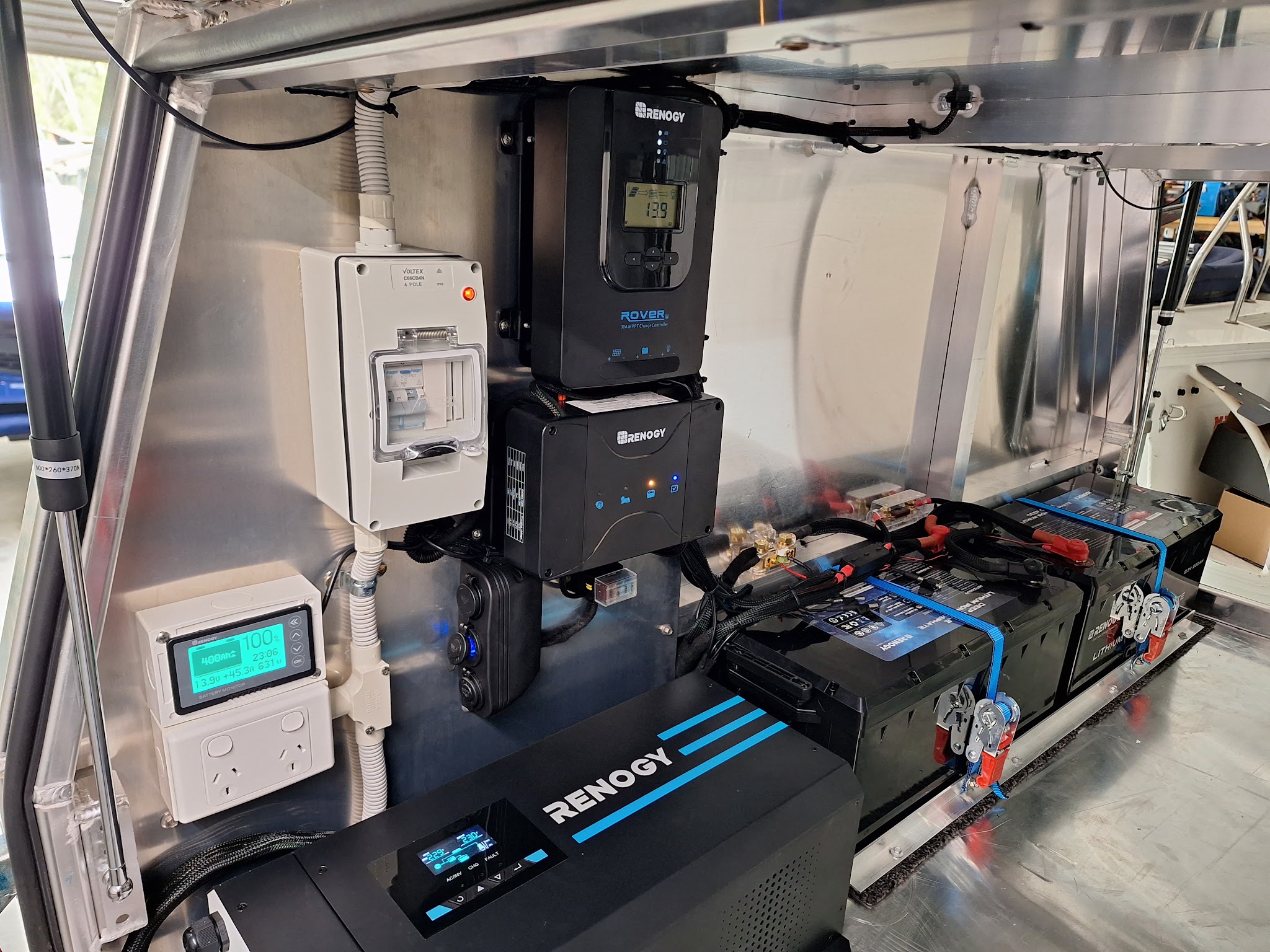 Camper 12V compartment with a solar charge controller, lithium batteries, an inverter and a battery monitor reading 100 percent